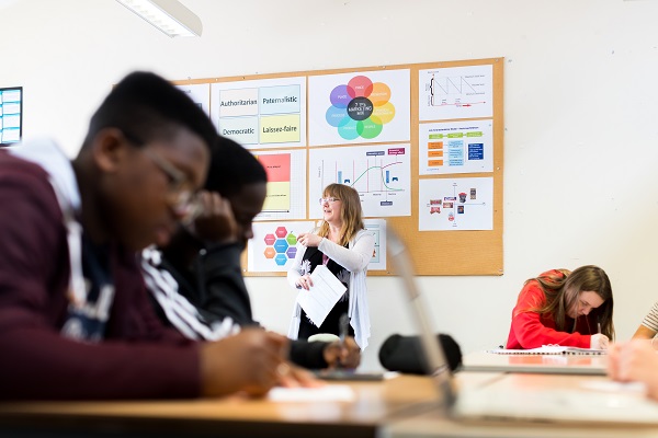 male students in class with teacher in background