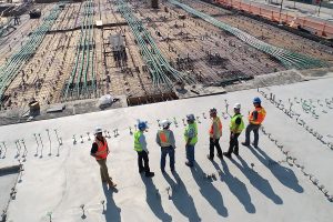 a row of men in hard hats overlooking a construction site