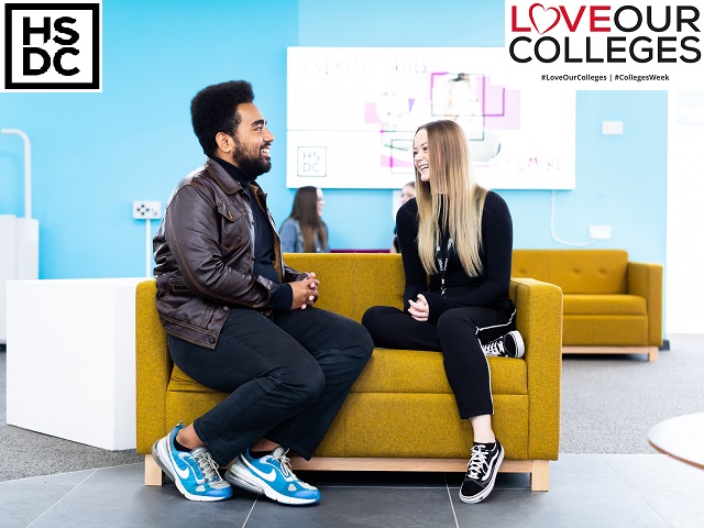 Students sat next to each other on a sofa talking and smiling