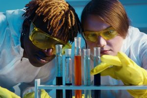 two students with goggles on looking at chemicals in test tubes