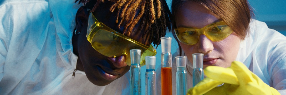 two students with goggles on looking at chemicals in test tubes