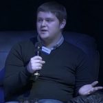 Will on stage at Shaping Portsmouth conference holding a microphone