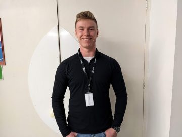 Thomas Brewer smiling against a white wall