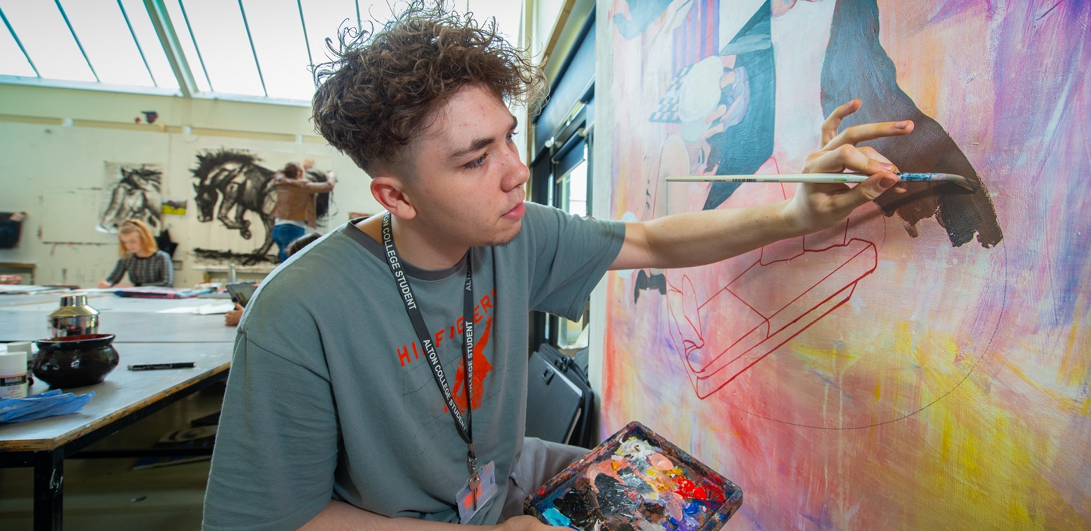 a male students painting a canvas