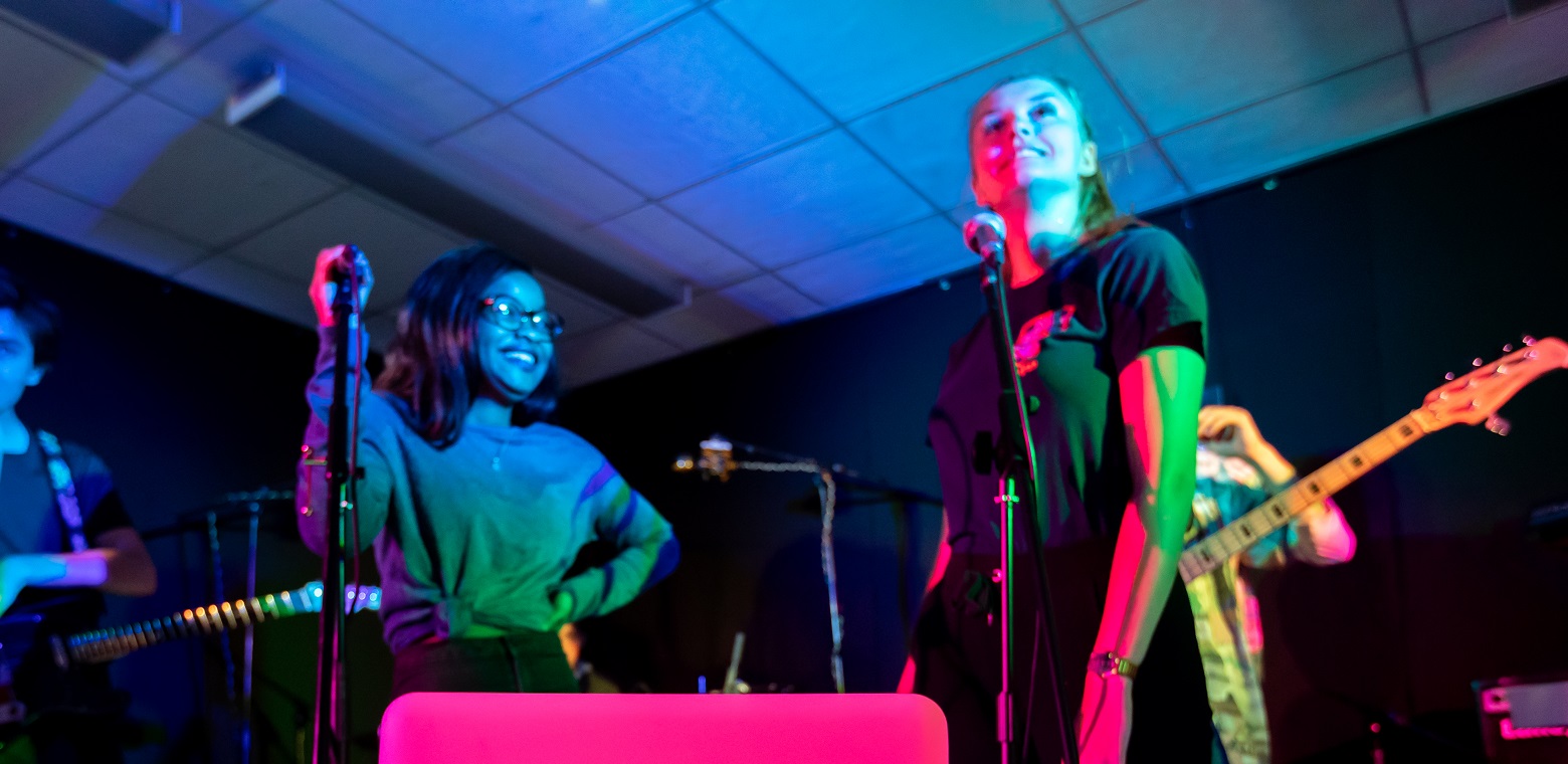 two female students standing in front of microphones