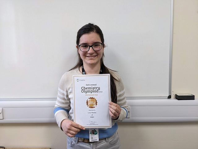 Lucy smiling with her gold award certificate