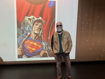 Artist Ian Churchill poses next to an artwork of Superman