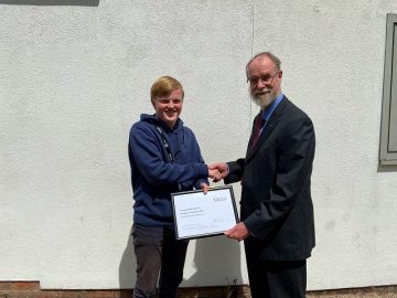 Kieran shaking hands with Steve while receiving his award