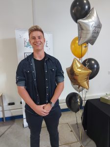 Thomas smiling with some multicoloured balloons