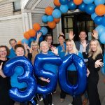 Staff from the NHS smiling with large balloons which say 350