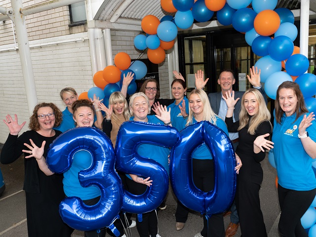 Staff from the NHS smiling with large balloons which say 350