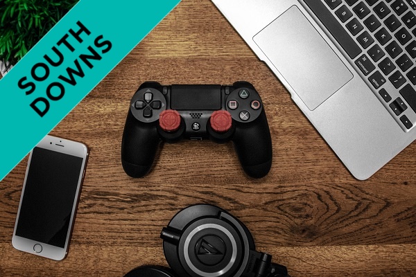 A game controller on a desk with a laptop beside it.