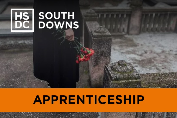 Closeup side profile of someone holding red flowers in a graveyard.