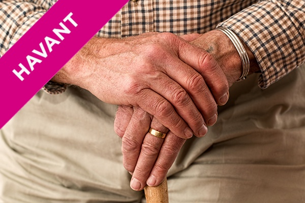 Closeup of an elderly man's hands on a walking stick.