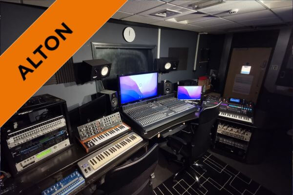 A photo of studio A, including two monitors, a large mixing desk, several stereo monitor speakers, midi keyboards and synthesizers as well as an analogue plugin rack.
