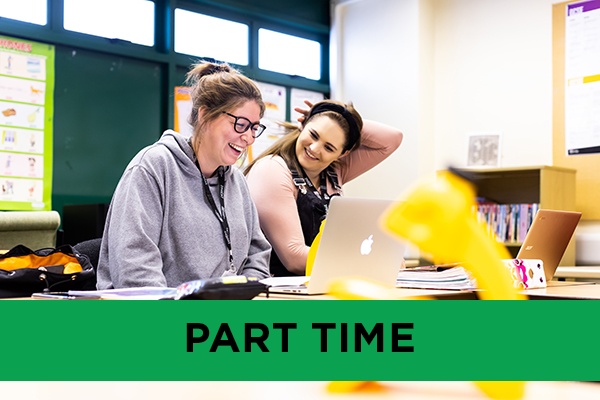 Two students smiling and laughing in class.