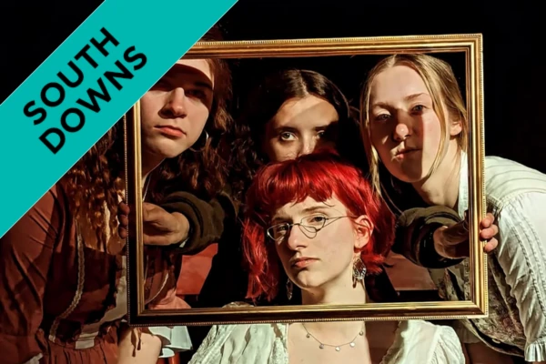 Four Students holding up a frame in period costumes as part of a performance.