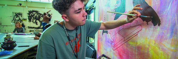 A Level Art and Design student painting a wall