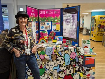 A representative from Open Access Arts poses next to her stall at the creative careers fair.