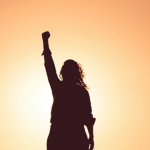 A silhouette of a woman raising her fist.