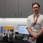 A student stands next to his engineering project.