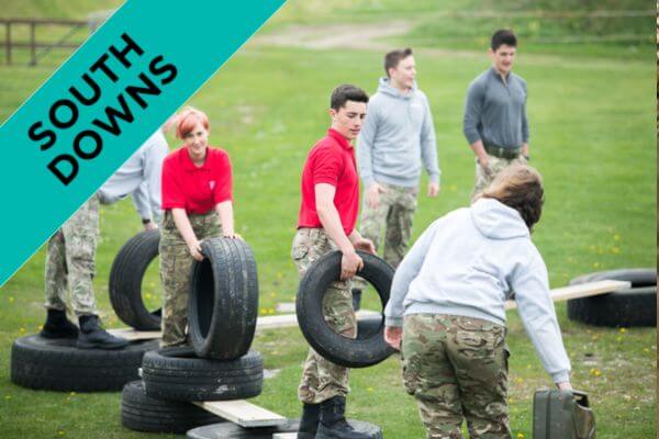 public services students in a field doing an obstacle course involving tires and planks