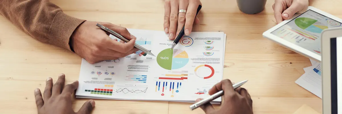 Multiple pairs of hands working on a business plan in the centre of a table.