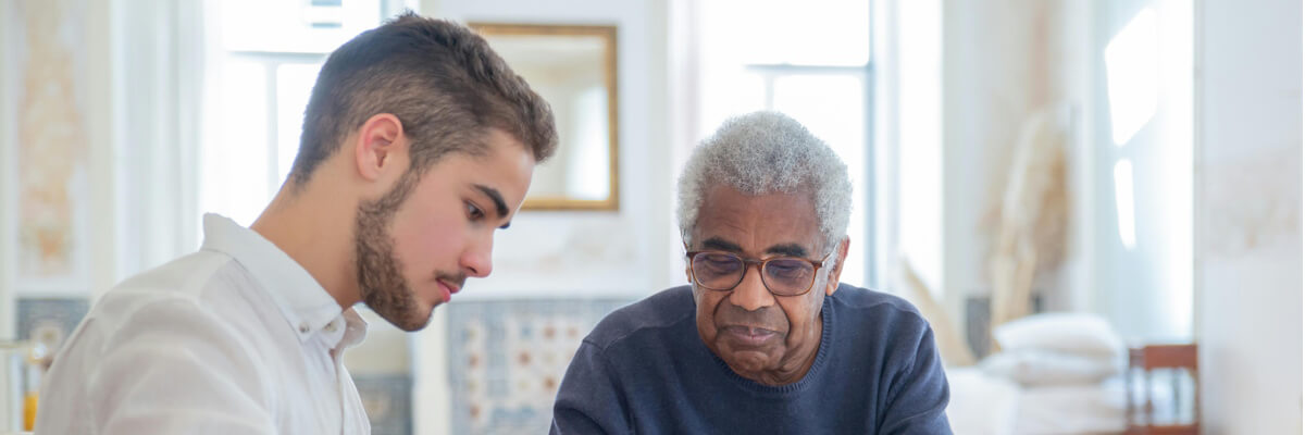 A young man helping an older gentleman.
