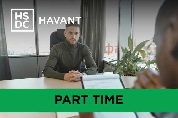 Two men in an interview setting, one reading a CV while the other talks.