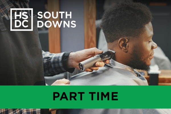 A barber using an electric trimmer to shave another man's neck.