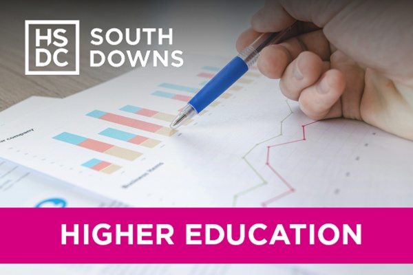 A hand holding a pen, hovering over some graphs on a piece of paper.