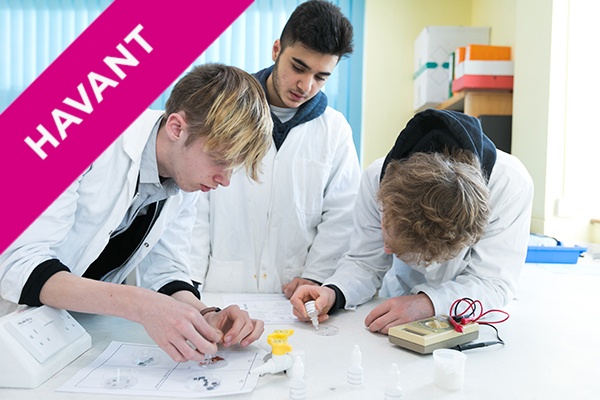 three students in lab coats in class