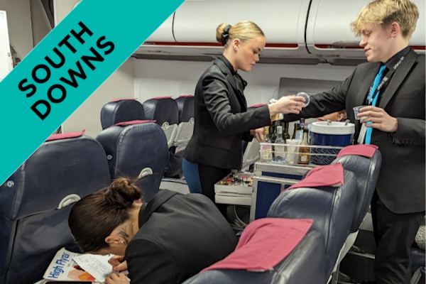 two students serving drinks from a trolley in our aviation suite.