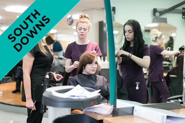 Two students work on a client's hair, with their lecturer's supervision.