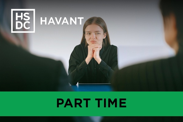 a woman in a black blazer in an interview setting, facing two others.