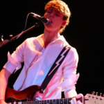 a student playing guitar while singing into a microphone