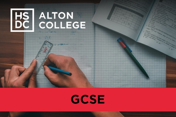 A person using a ruler to do maths work with a textbook beside them.