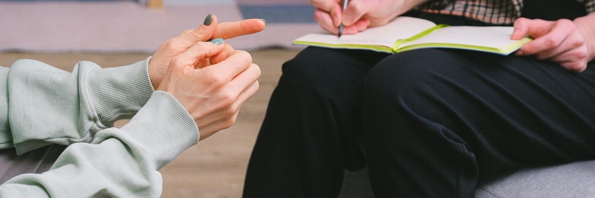 Two people in a counselling session, one taking notes.
