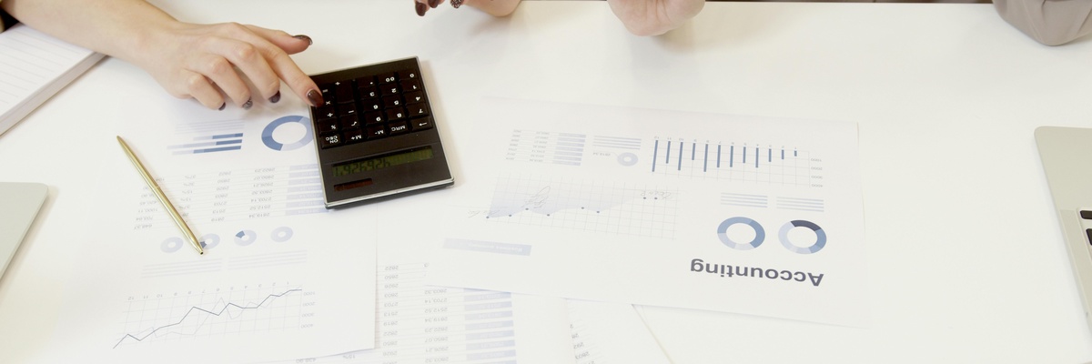 A person using a calculator to analyse accounting graphs.