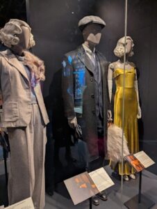 A group of outfits on mannequins with information plaques.