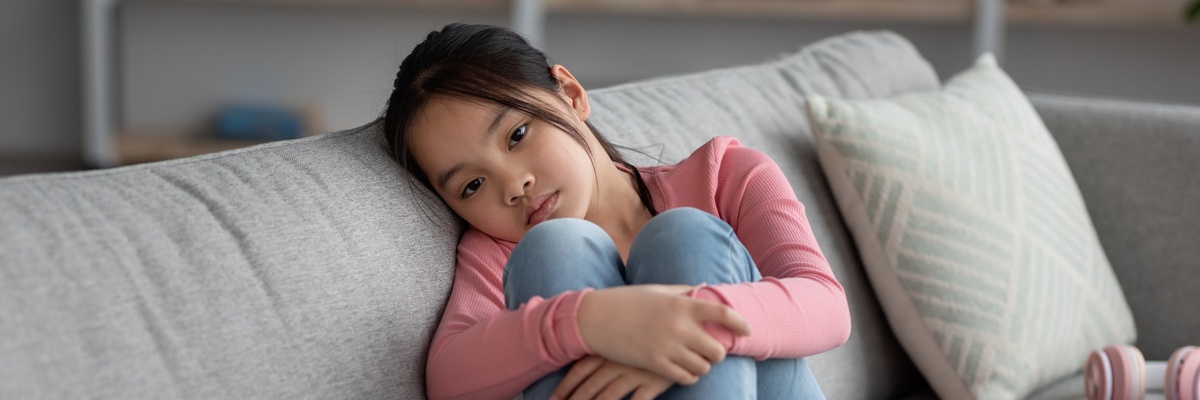 A sad looking child hugging their knees.