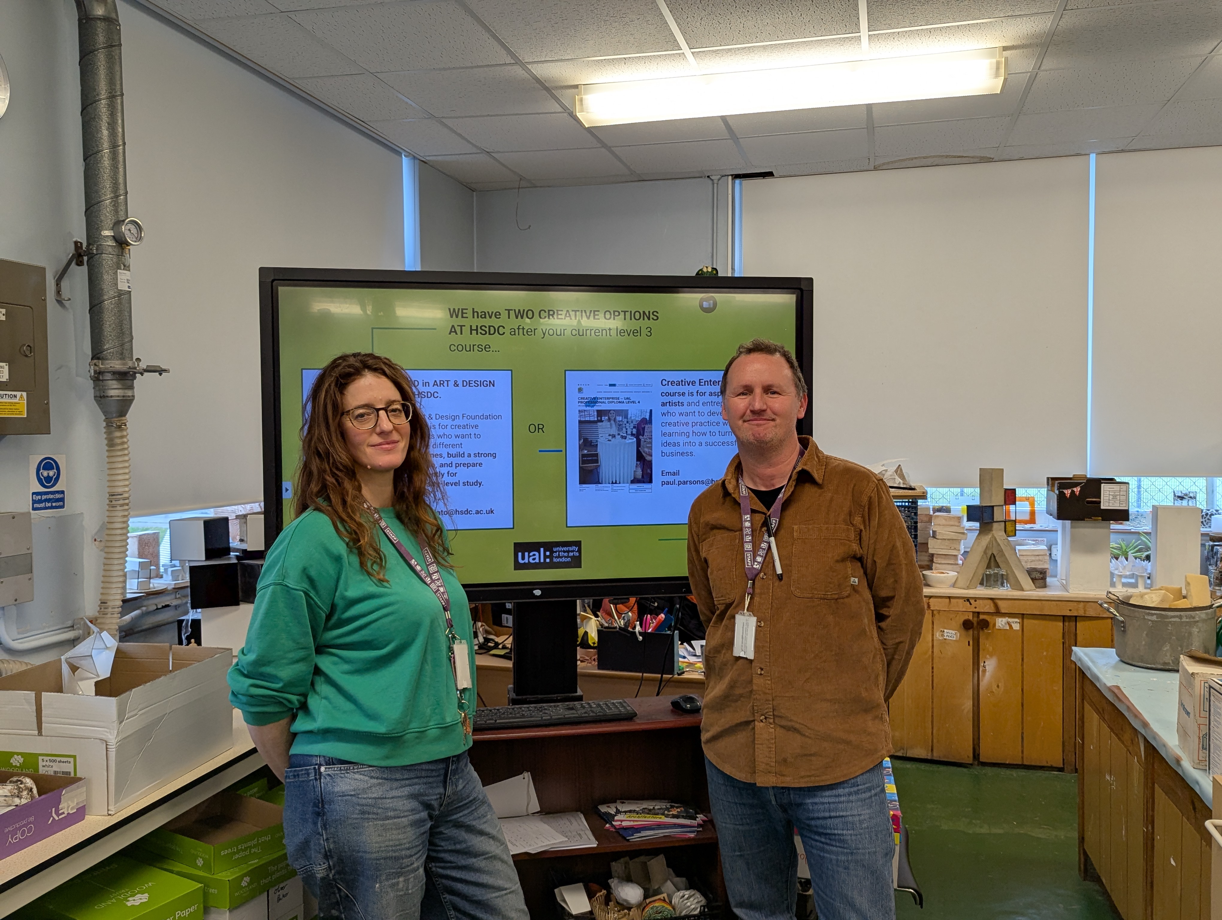 Two HSDC Art Lecturers pose in front of a presentation screen.