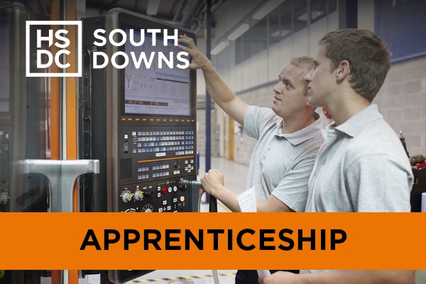 An engineering technician teaches an apprentice how to use a computer system.