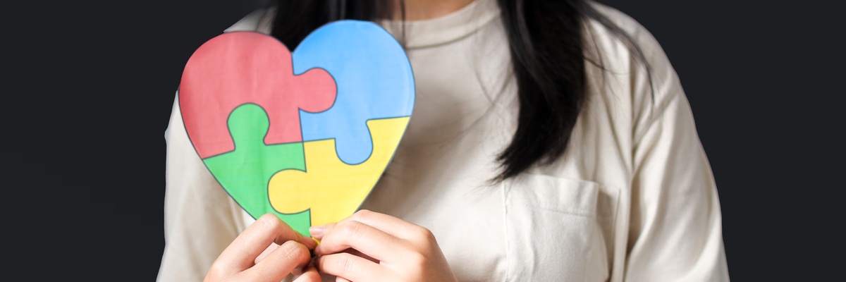 A woman holding a colourful heart-shaped jigsaw.
