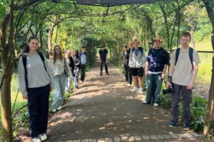 A group of students posing in a natural arched walkway.
