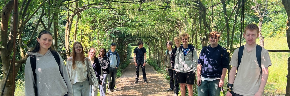 A group of students posing in a natural arched walkway.