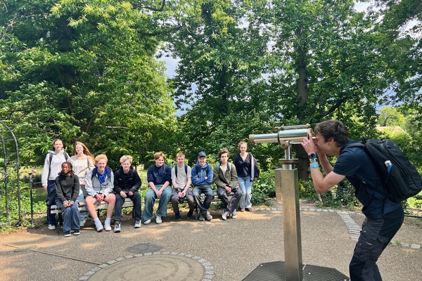 A group of students on a trip, as the lecturer looks through a telescope.