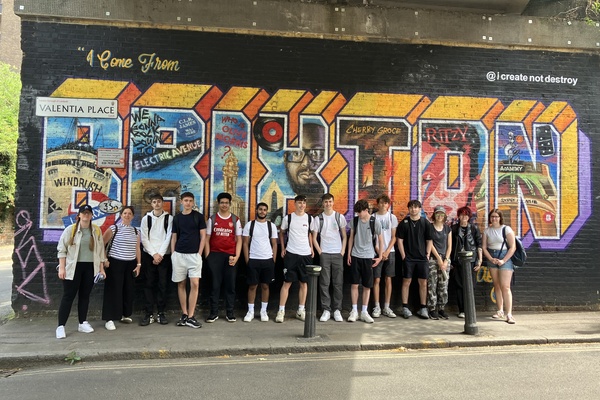 A group of Geography students in front of a mural in Brixton.